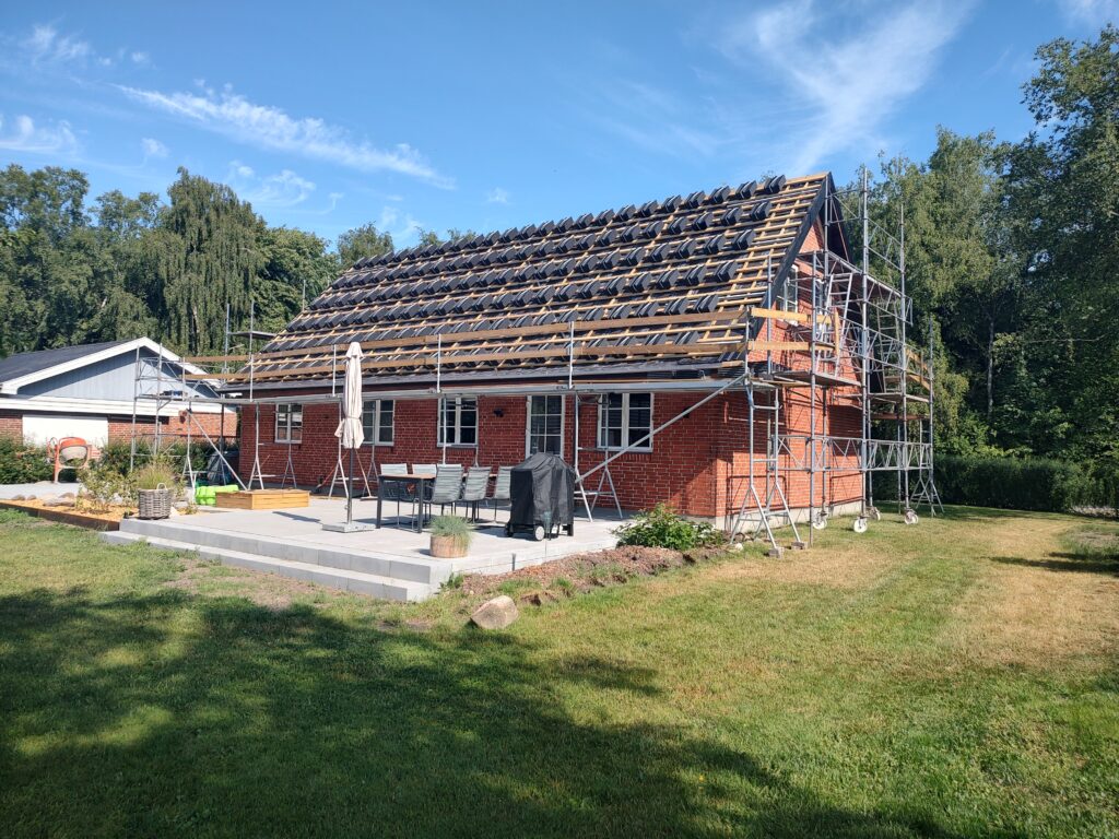 Murstenhus under tagrenovering med stillads
