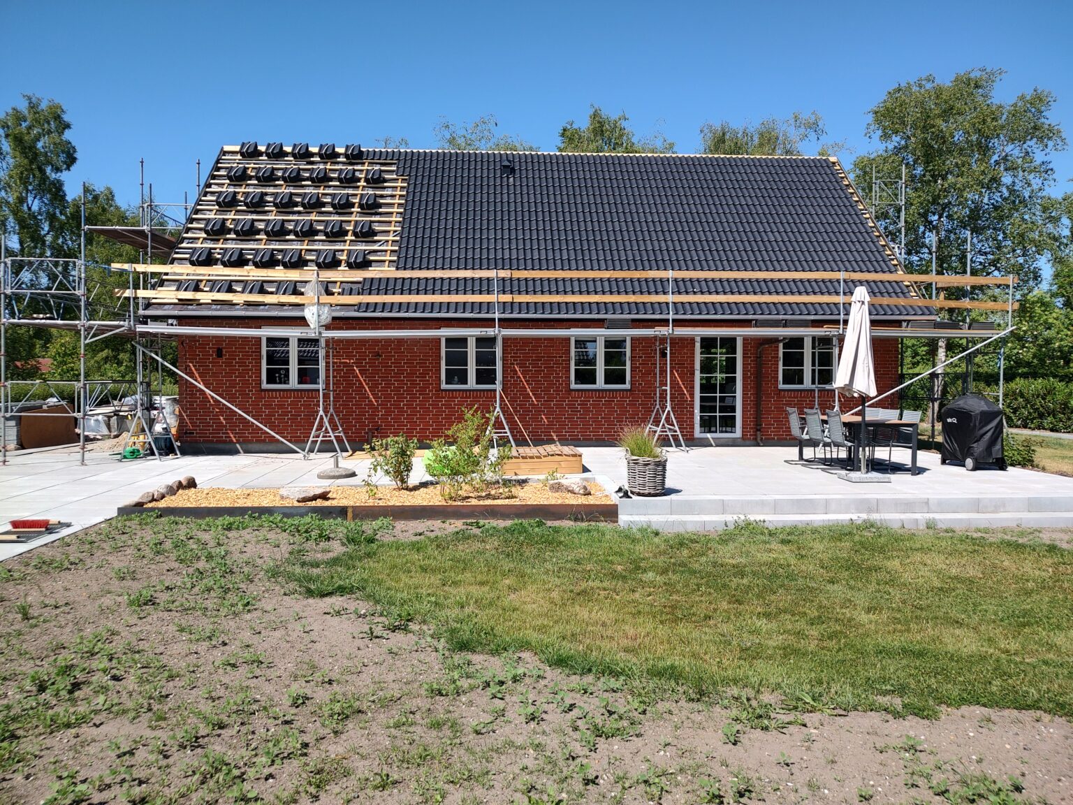 Murstenhus med stillads og tagrenovering