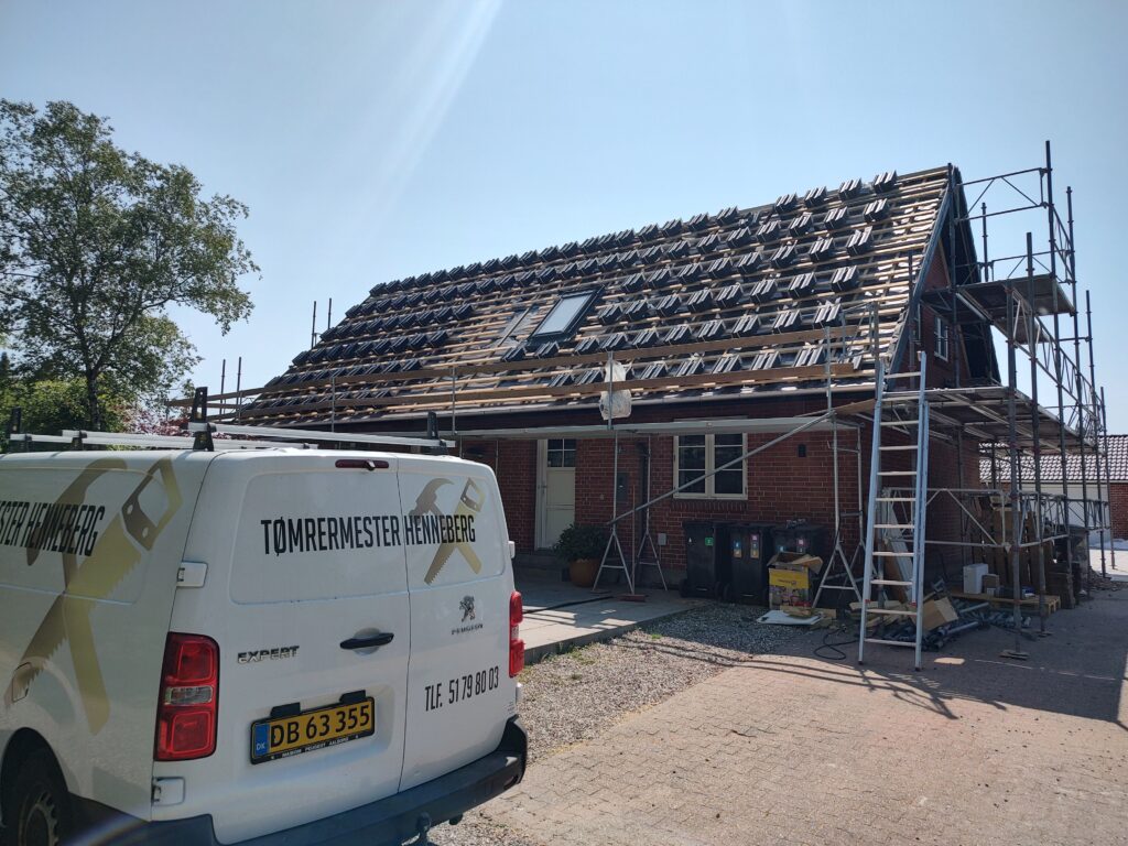 Hus under tagrenovering med stillads og håndværkerbil